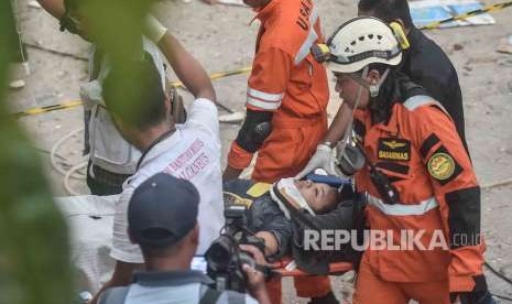 Petugas Basarnas membawa korban selamat gempa dan tsunami yang terjebak di dalam restoran Dunia Baru, Palu, Sulawesi Tengah, Ahad (30/9).