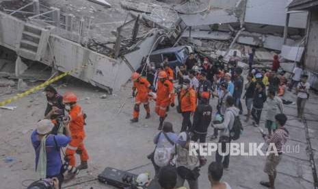 Petugas Basarnas membawa korban selamat gempa dan tsunami yang terjebak di dalam restoran Dunia Baru, Palu, Sulawesi Tengah, Ahad (30/9).