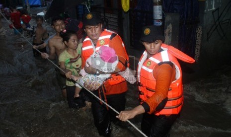   Petugas Basarnas mengevakuasi korban banjir di kawasan Kampung Pulo, Jakarta, Ahad (12/1).  (Republika/Yasin Habibi)