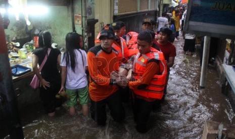   Petugas Basarnas mengevakuasi korban banjir di kawasan Kampung Pulo, Jakarta, Ahad (12/1).  (Republika/Yasin Habibi)