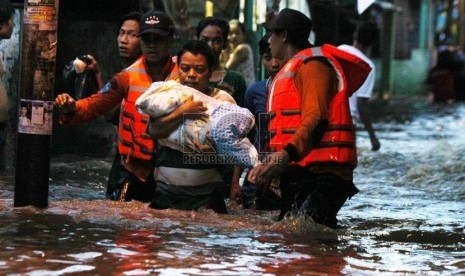   Petugas Basarnas mengevakuasi korban banjir di kawasan Kampung Pulo, Jakarta, Ahad (12/1).  (Republika/Yasin Habibi)