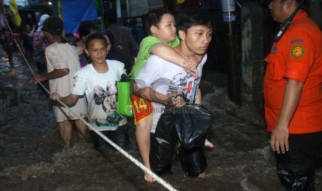   Petugas Basarnas mengevakuasi korban banjir di kawasan Kampung Pulo, Jakarta, Ahad (12/1).  (Republika/Yasin Habibi)