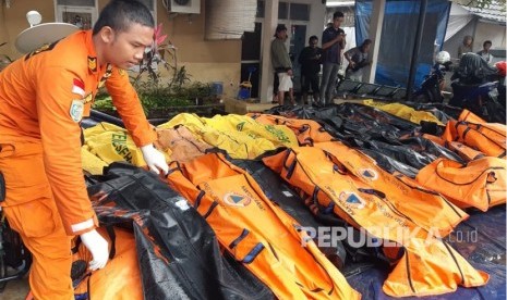 Petugas Basarnas mengumpulkan jenazah korban tsunami di pesisir Cinangka, Serang, Banten, Ahad (23/12).