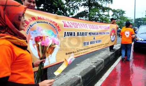 Petugas Bawaslu Jabar memperlihatkan bunga dan stiker sebagai bentuk sosialisasi pemilu bersih di Jalan Surapati, Bandung, Kamis(27/3).  (foto: Septianjar Muharam)