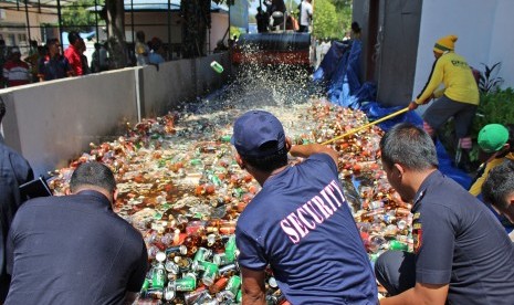 Petugas bea cukai melemparkan botol dan kaleng minuman keras (miras) ke arah alat berat saat pemusnahan miras selundupan di Halaman Kantor Bea Cukai Kabupaten Nunukan, Kalimantan Utara, Rabu (16/3).