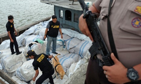 Petugas Bea dan Cukai bersama anjing pelacak membantu memeriksa barang bukti tumpukan bal berisi pakaian bekas. ilustrasi