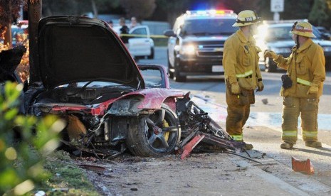   Petugas berada di lokasi mobil Porsche yang hancur menabrak tiang lampu di Hercules Street, Valencia, California,  Sabtu (30/11) waktu setempat.  (AP)