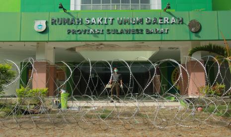 Petugas berdiri di belakang kawat berduri yang dipasang di depan ruangan isolasi covid-19 RSUD Sulbar, Mamuju, Sulawesi Barat, Selasa (14/4/2020). Pagar kawat berduri yang dipasang membentang di depan ruang isolasi covid-19 RSUD Sulbar tersebut bertujuan menghindari pasien isolasi kabur dan untuk pembatasan pengunjung masuk.