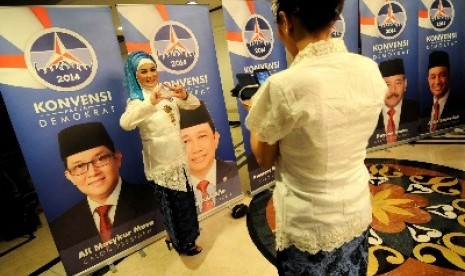 Petugas berfoto di depan poster konvensi calon presiden Partai Demokrat di Jakarta, Ahad (15/9) malam. Konvensi calon presiden Partai Demokrat diikuti oleh 11 orang calon baik dari dalam partai atau non partai.