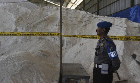 Petugas berjaga di depan garam milik PT Garam (persero) yang disegel di dalam gudang oleh Tim Satgas Pangan Mabes Polri di Gresik, Jawa Timur, Rabu (7/6). 