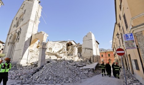 Petugas berjalan di reruntuhan katedral di Norcia, Italia, (31/10). Italia kembali diguncang gempa kuat.