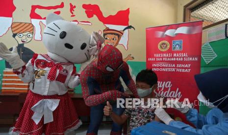 Petugas berkostum super hero Spiderman dan tokoh Hello Kitty mendampingi seorang anak saat vaksinasi COVID-19 dosis ke-2 untuk anak usia 6-11 tahun di SD N 1 Keceme, Caturharjo, Sleman, D.I Yogyakarta, Sabtu (19/2/2022). Vaksinasi bersama super hero tersebut guna meningkatkan minat anak-anak mengikuti vaksinasi COVID-19 dosis ke-2.