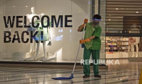 Petugas bermasker dan berpelindung wajah membersihkan lantai di Mal Central Park, Jakarta.