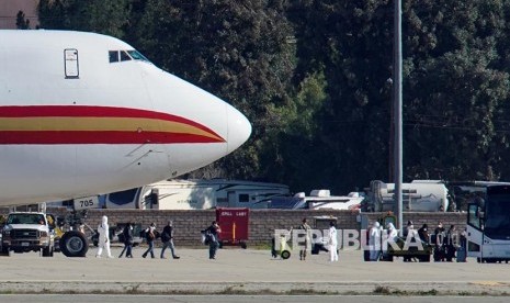 Petugas berpakaian pelindung menurunkan warga AS yang dievakuasi dari Kota Wuhan, Hubei, China mendarat di March Air Reserve Base, Riverside County, California, Amerika Serikat, Rabu (29/1) waktu setempat. Sudah 15 orang di AS terkonfirmasi positif infeksi virus corona tipe baru, Covid-19. 