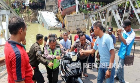 Petugas bersama warga mengevakuasi sepeda motor yang tercebur dalam kejadian runtuhnya jembatan Widang, di Tuban, Jawa Timur, Selasa (17/4). 