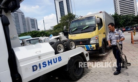  Petugas bersiap mengembok roda mobil usai diderek di Kawasan IRTI, Monas, Jakarta, Senin (3/4). 