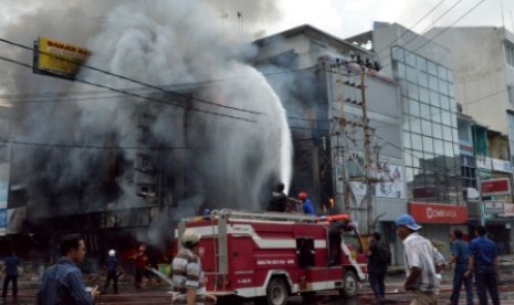 Petugas berupaya memadamkan kebakaran pertokoan elektronik di Jalan Masjid Lama Pasar 16 Ilir Palembang, Sumsel, Selasa (4/6). Polisi memastikan kalau kebakaran tersebut disengaja terkait dengan pilkada wali kota setempat.