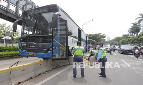 Petugas berupaya mengevakuasi bus TransJakarta yang menabrak separator di Jalan Jenderal Sudirman, Jakarta, Jumat (3/12/2021). Menurut petugas penyebab kecelakaan bus TransJakarta bernomor polisi B 7277 TGC itu diduga akibat sopir yang kurang konsentrasi saat mengemudi. 