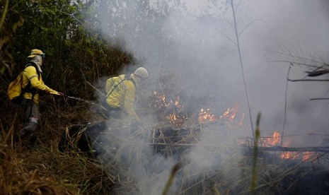 Petugas berusaha memadamkan api di sepanjang jalan ke Jacunda National Forest, dekat kota Porto Velho di kawasan Vila Nova Samuelyang merupakan bagian dari hutan Amazon, Senin (26/8).