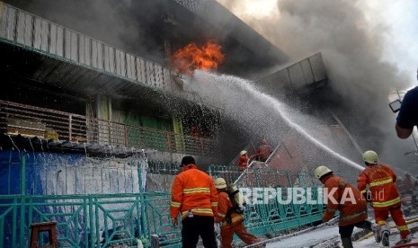 Petugas berusaha memadamkan api yang membakar bangunan Blok I dan Blok II yang terbakar di Pasar Senen, Jakarta, Kamis (19/1).