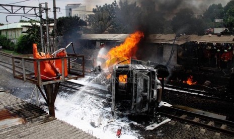   Petugas berusaha memadamkan mobil tangki yang terbakar, setelah ditabrak KRL Commuterline jurusan Serpong-Jakarta di perlintasan kereta di Bintaro Permai, Tangerang Selatan, Senin (9/12). (Republika/Yasin Habibi)