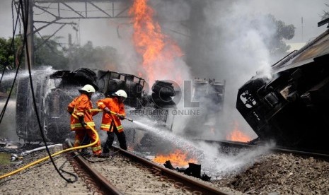   Petugas berusaha memadamkan mobil tangki yang terbakar, setelah ditabrak KRL Commuterline jurusan Serpong-Jakarta di perlintasan kereta di Bintaro Permai, Tangerang Selatan, Senin (9/12). (Republika/Yasin Habibi)