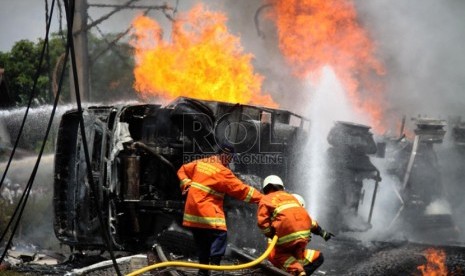   Petugas berusaha memadamkan mobil tangki yang terbakar, setelah ditabrak KRL Commuterline jurusan Serpong-Jakarta di perlintasan kereta di Bintaro Permai, Tangerang Selatan, Senin (9/12). (Republika/Yasin Habibi)