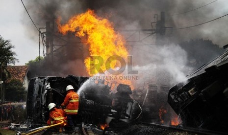   Petugas berusaha memadamkan mobil tangki yang terbakar, setelah ditabrak KRL Commuterline jurusan Serpong-Jakarta di perlintasan kereta di Bintaro Permai, Tangerang Selatan, Senin (9/12). (Republika/Yasin Habibi)