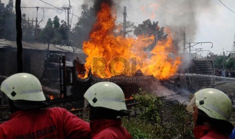   Petugas berusaha memadamkan mobil tangki yang terbakar, setelah ditabrak KRL Commuterline jurusan Serpong-Jakarta di perlintasan kereta di Bintaro Permai, Tangerang Selatan, Senin (9/12). (Republika/Yasin Habibi)