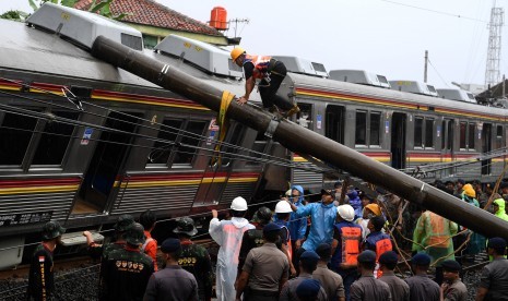 Petugas berusaha memindahkan tiang listrik yang menimpa gerbong KRL Commuter Line 1722 yang anjlok di pintu perlintasan Kebon Pedes, Tanah Sareal, Kota Bogor, Jawa Barat, Ahad (10/3/2019).