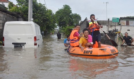 Petugas BNPB mengevakuasi warga akibat banjir di kawasan perumahan jalan Pura Demak, Denpasar, Sabtu (8/12/2018).