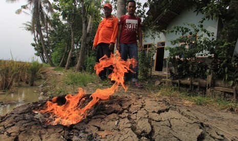 Petugas BPBD bersama warga mengamati api dari semburan gas yang muncul di permukiman di desa Sukaperna, Kecamatan Tukdana, Indramayu, Jawa Barat, Sabtu (30/12).