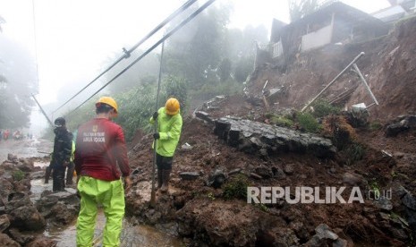 Petugas BPBD Kabupaten Bogor berusaha membersihkan material longsor yang menutupi jalur utama Puncak Bogor, Jawa Barat, Senin (5/2).