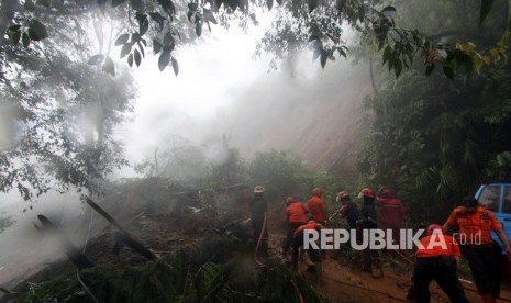 Petugas BPBD Kabupaten Bogor berusaha membersihkan material longsor yang menutupi jalur utama Puncak Bogor, Jawa Barat, Senin (5/2).