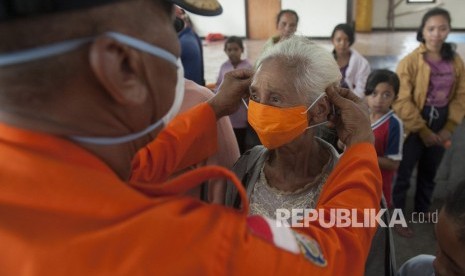 Petugas BPBD memasangkan masker pada seorang pengungsi Gunung Agung di lokasi penampungan Desa Bebandem, Karangasem, Bali.