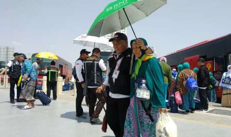 Petugas Daker Bandara memayungi jamaah lansia di Bandara Amir Muhammad bin Abdulaziz, Madinah, Rabu (12/9).