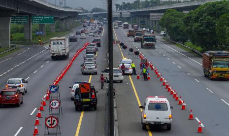 Petugas dan anggota polisi mengatur laju kendaraan yang melintas menuju arah Jakarta saat pemberlakuan sistem contraflow di Tol Jakarta-Cikampek, Karawang, Jawa Barat, Senin (16/5/2022). PT Jasa Marga (Persero) Tbk akan memberlakukan diskon sebesar 20 persen untuk tarif terjauh Jalan Tol Jakarta-Cikampek (Japek).