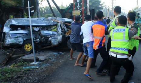 Petugas dan warga memindahkan mobil Mitsubisi L300 bernopol P 1264 DE yang ringsek akibat kecelakaan dengan kereta api di lintasan rel di Dusun Rohkepuh, Beji, Pasuruan, Jawa Timur, Rabu (9/1/2019).