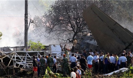 Petugas dan warga menyaksikan bangkai pesawat Fokker 27 yang jatuh dan terbelah di komplek perumahan Rajawali kawasan Lapangan Udara Halim Perdana Kusuma, Jakarta, Kamis (21/6). 