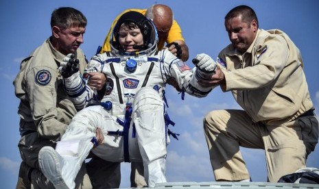 Petugas darat membantu astronot Anne McClain (tengah).