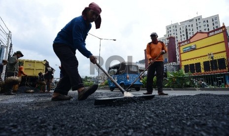 Petugas dari Dinas Bina Marga memperbaiki jalan yang berlubang di Jalan Otista, Jakarta Timur, Senin (23/2).  (Republika/Raisan Al Farisi)