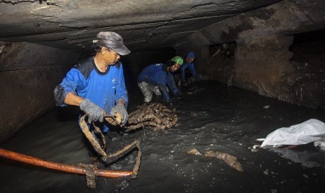 Petugas dari Dinas Tata Air Pemprov DKI Jakarta mengangkat kulit kabel yang menyumbat gorong-gorong di kawasan Jalan Merdeka Selatan, Jakarta, Jumat (4/3). 