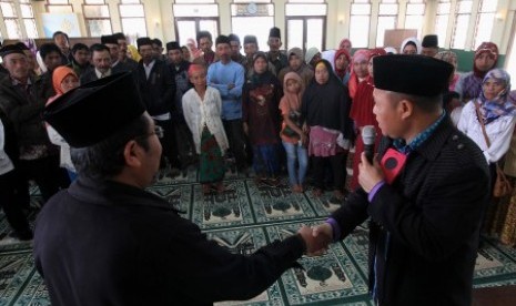 Petugas dari KUA mengajarkan cara ijab kabul kepada warga peserta pernikahan massal gratis di Masjid Mujahidin, Tosari, Pasuruan, Jawa Timur, Jumat (23/10). 