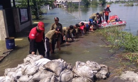 Petugas dari Pemkot Surabaya mengangkut handbag menggunakan perahu boat untuk menutup tanggul Anak Kali Lamong yang jebol di RW 03, Kelurahan Sumberejo, Kecamatan Pakal, Kota Surabaya, Jumat (3/5).