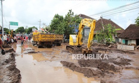 Petugas dengan alat berat membersihkan lumpur akibat banjir bandang yang melanda Banyuwangi, Jawa Timur, Jumat (22/6).