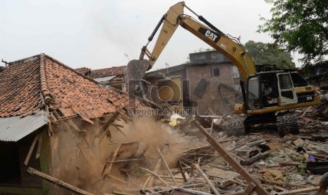 Petugas dengan alat berat merobohkan bangunan saat penggusuran pemukiman liar di Kampung Pulo, Jatinegara, Jakarta, Kamis (20/8).