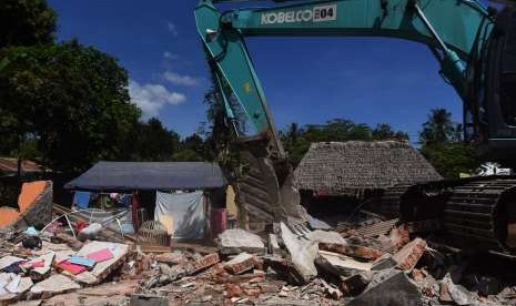 Petugas dengan alat berat merobohkan rumah yang rusak akibat gempa bumi di Kayangan, Lombok Utara, NTB, Minggu (12/8).