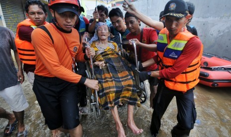 Petugas dengan dibantu warga mengevakuasi lansia yang terkena dampak banjir