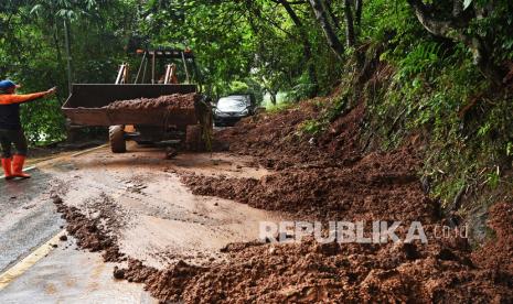 Petugas dengan menggunakan alat berat membersihkan material longsor yang menutupi badan jalan di Jalan Raya Serang-Anyer, Kampung Cilowong, Taktakan, Serang, Banten, Sabtu (3/4). Longsor terjadi setelah terjadi hujan deras sejak Jumat (2/4) sore di lokasi tersebut. 