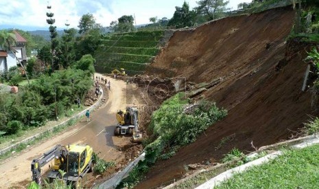 Petugas dengan menggunakan alat berat membersihkan sisa longsor tebing di Ciloto Puncak, Jabar,Kamis (10/1). (Republika/Musiron)